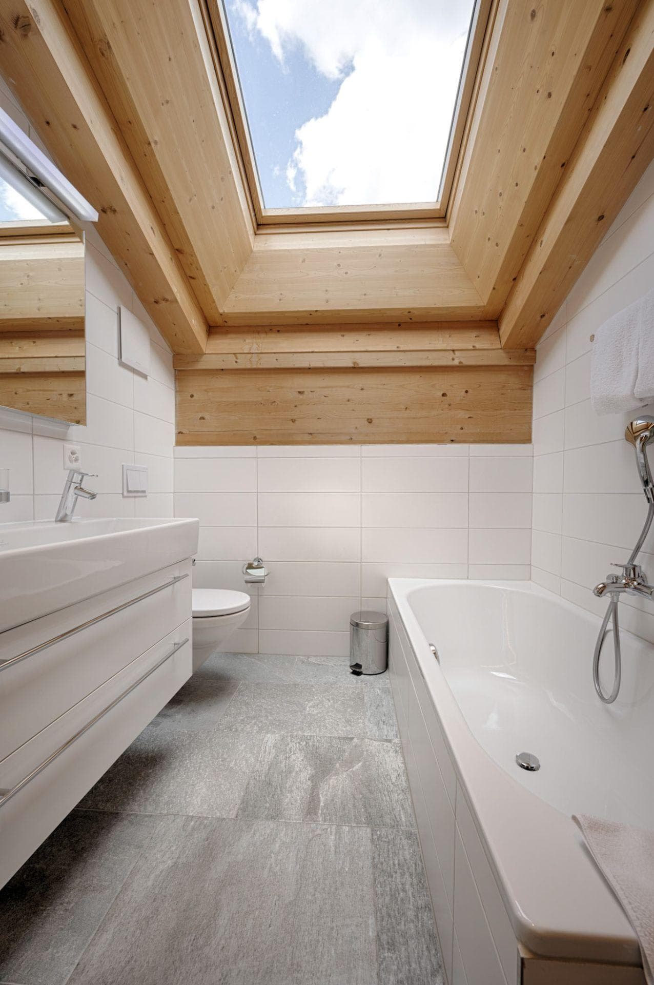 Bathroom with soaking tub and skylight over exposed timber beams