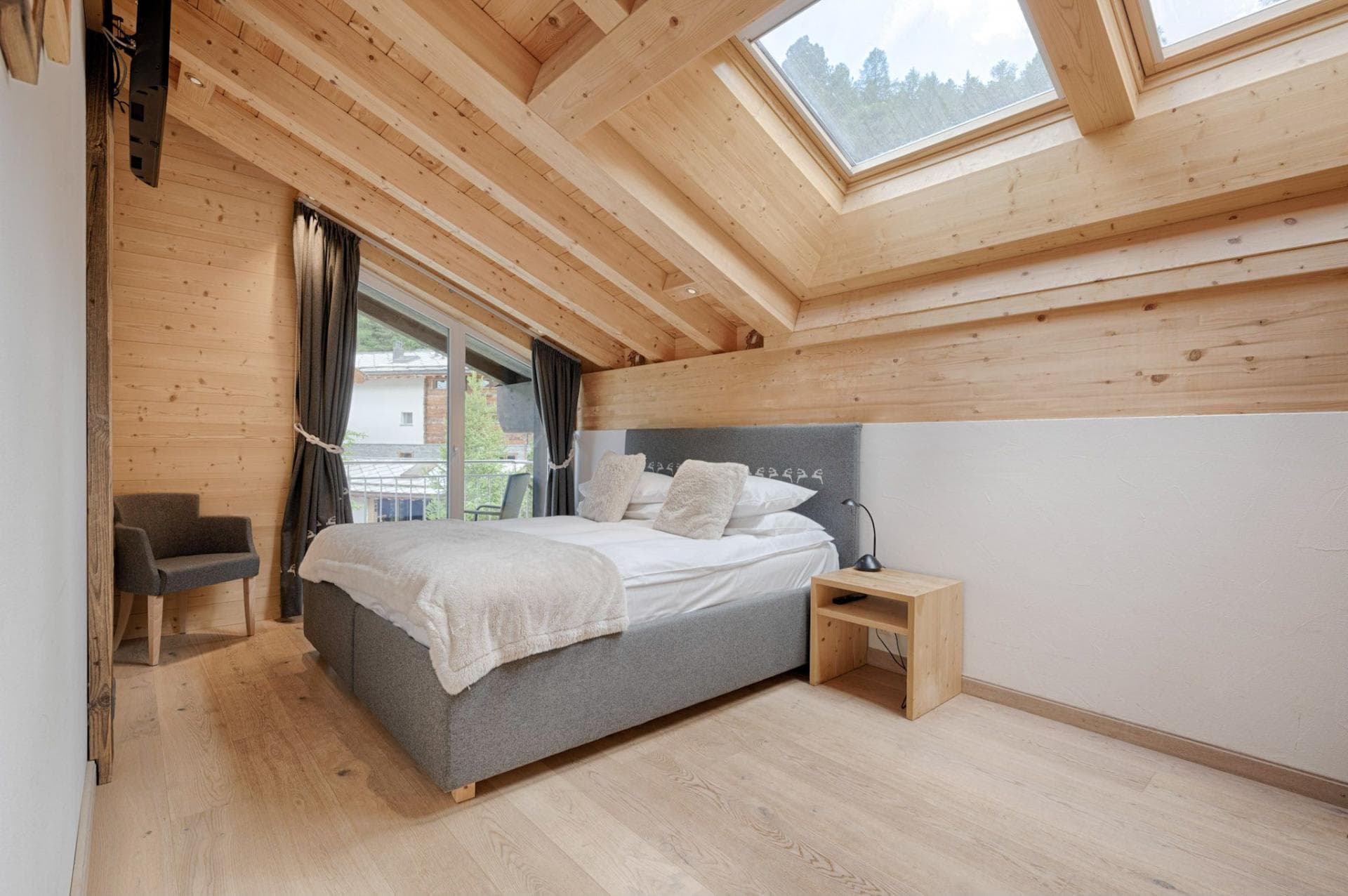 Attic bedroom with queen bed, skylight, and private balcony access