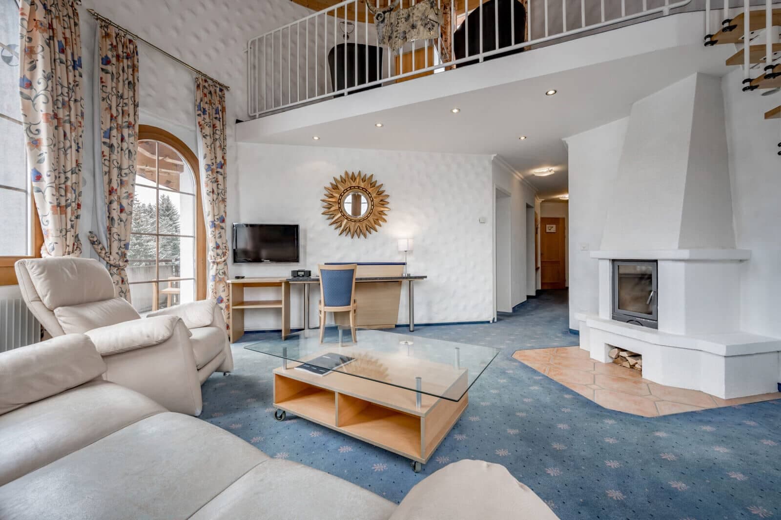 Living area with wood-burning fireplace, desk, and sleeping loft above
