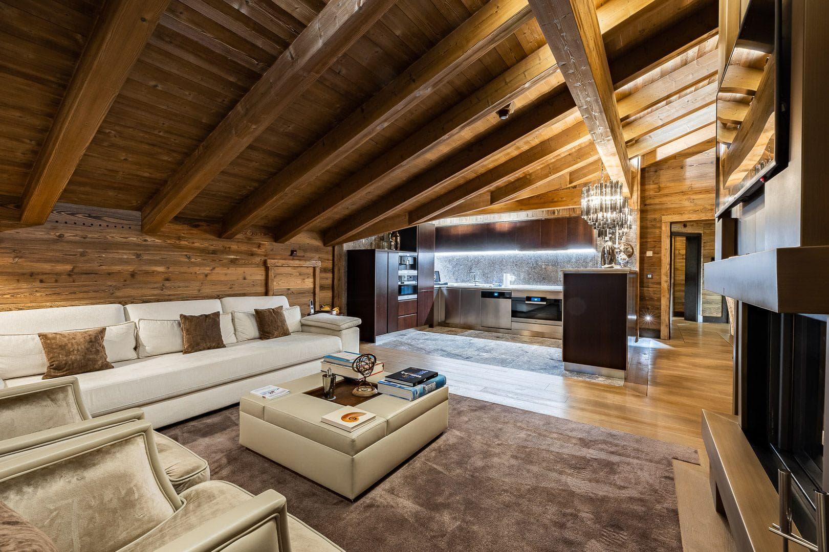 Open living area with vaulted wood-beam ceilings and kitchenette