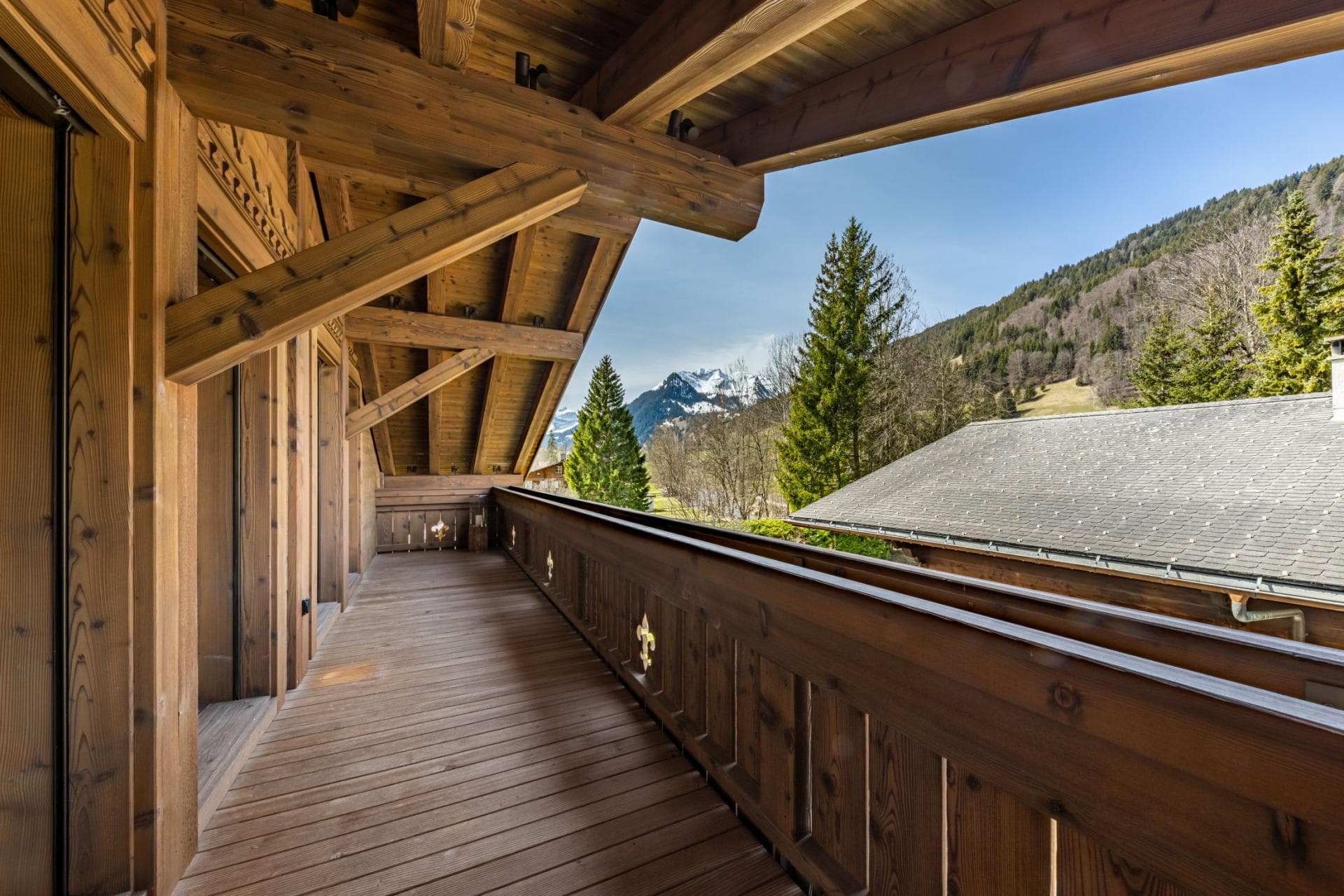 Covered wooden balcony with mountain views and fleur-de-lis cutouts