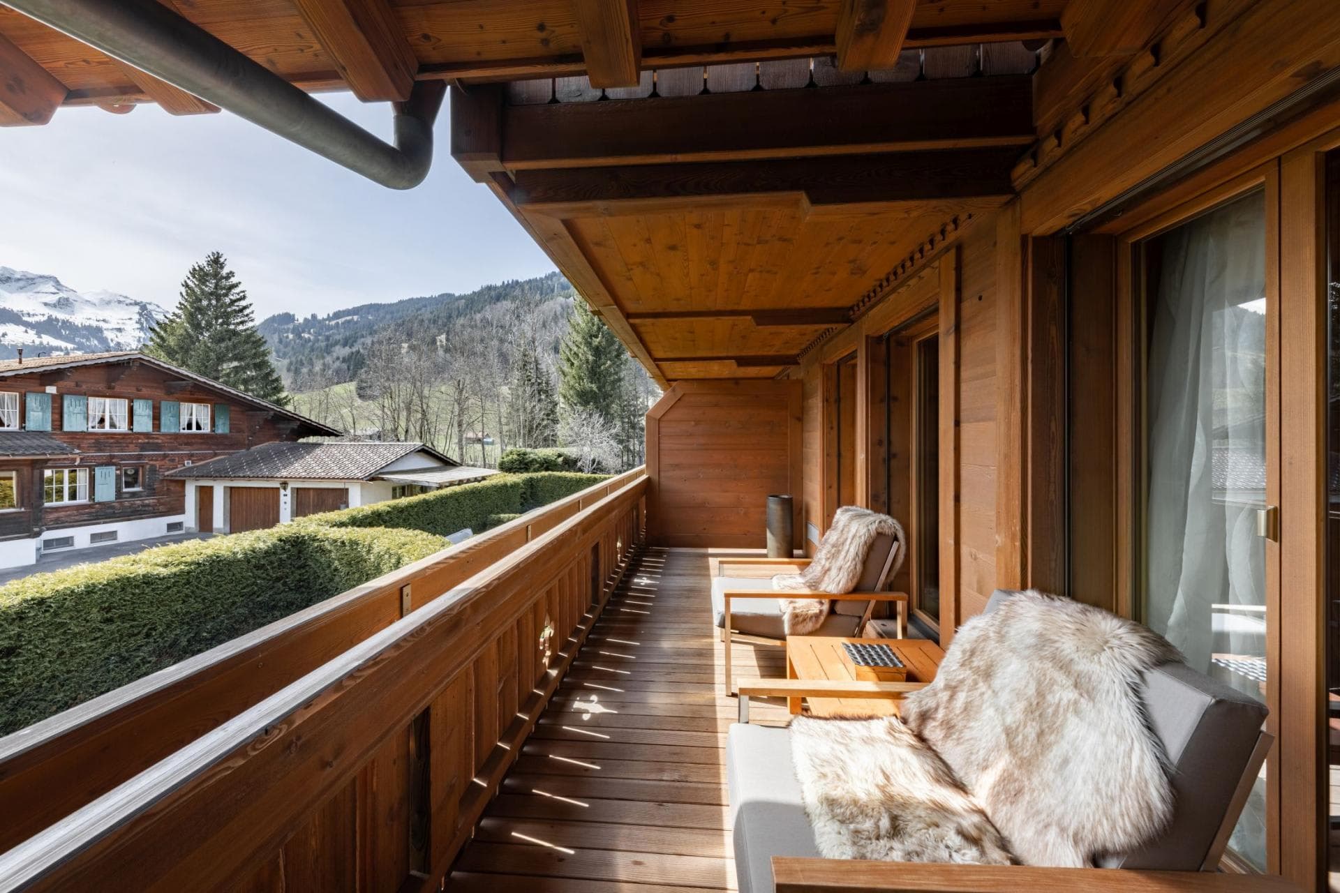 Covered wooden balcony with lounge seating and mountain views