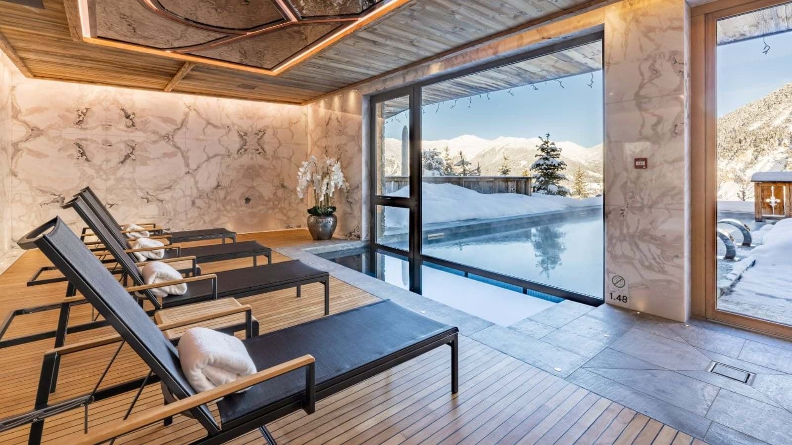 Indoor-outdoor heated pool and lounge area with mountain views