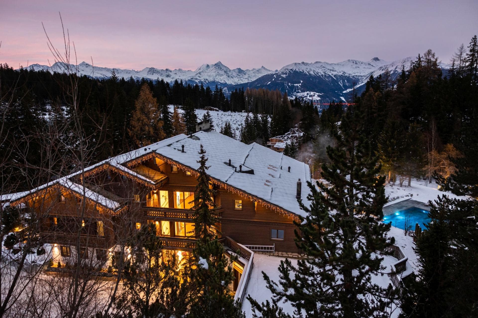Chalet exterior with heated outdoor pool and panoramic alpine views