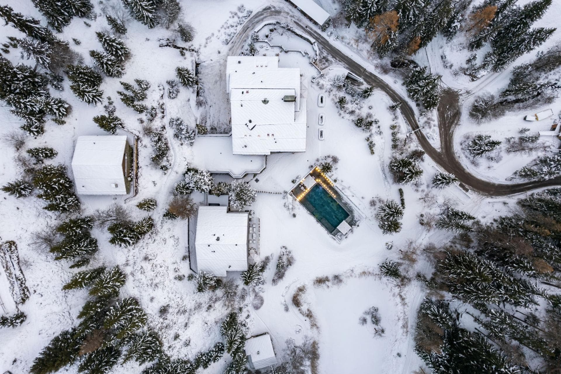 Aerial view of chalet estate featuring heated outdoor pool and forested grounds