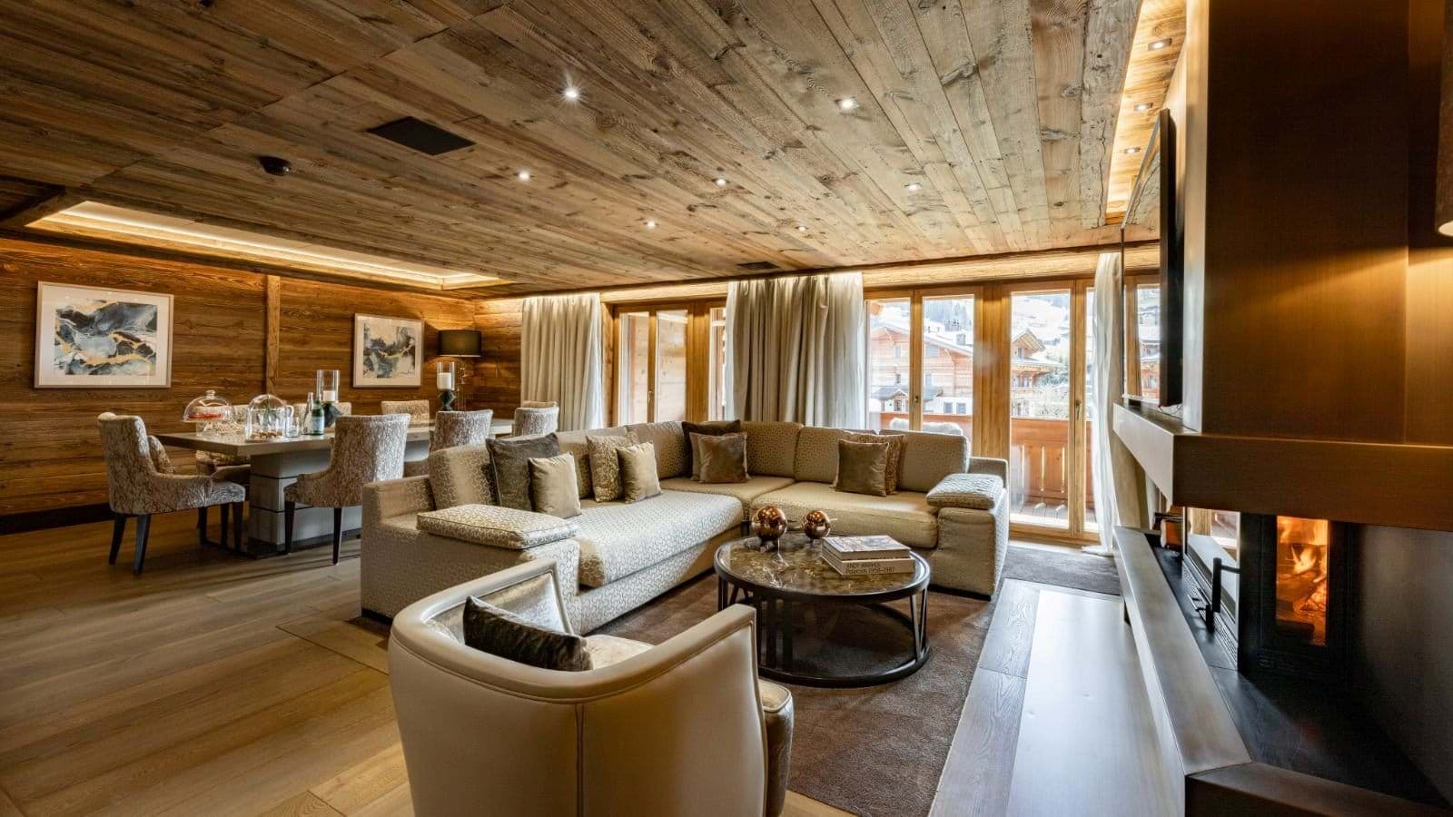 Open living area with wood-clad ceilings and fireplace; balcony access