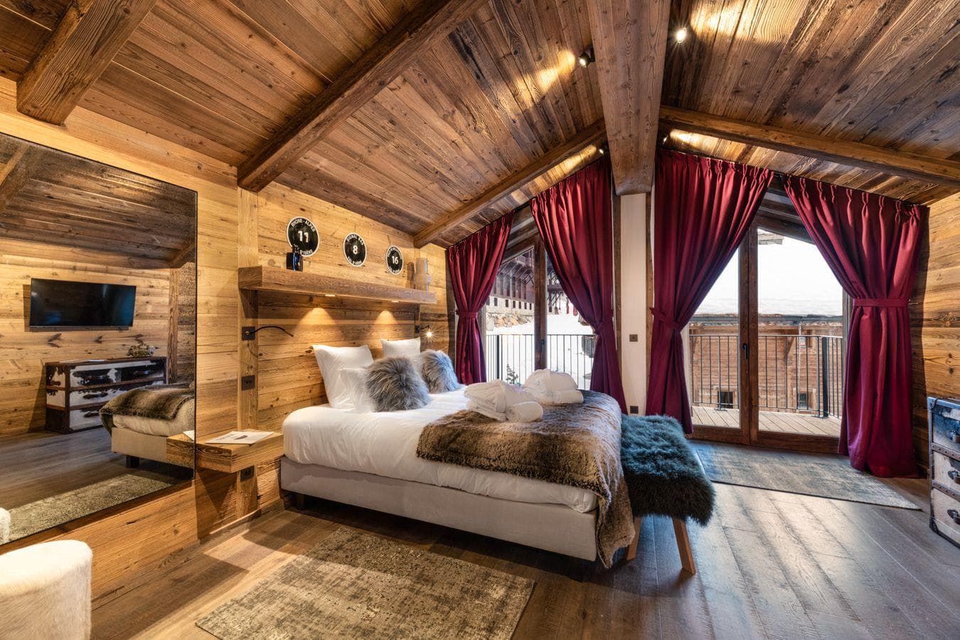 Primary bedroom with king bed, vaulted wood ceilings, and private balcony access
