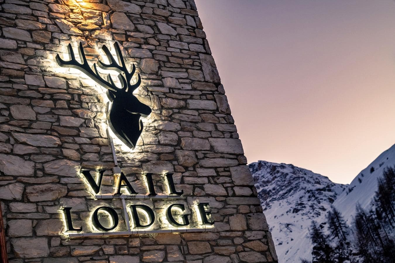 Stone lodge exterior with illuminated signage and mountain views