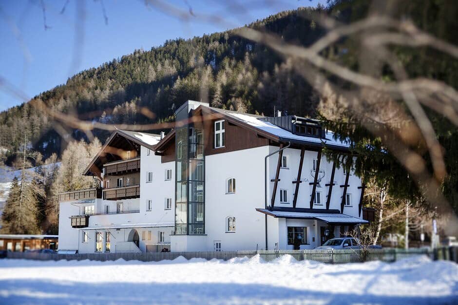 Chalet exterior with glass elevator and private balconies; forest backdrop