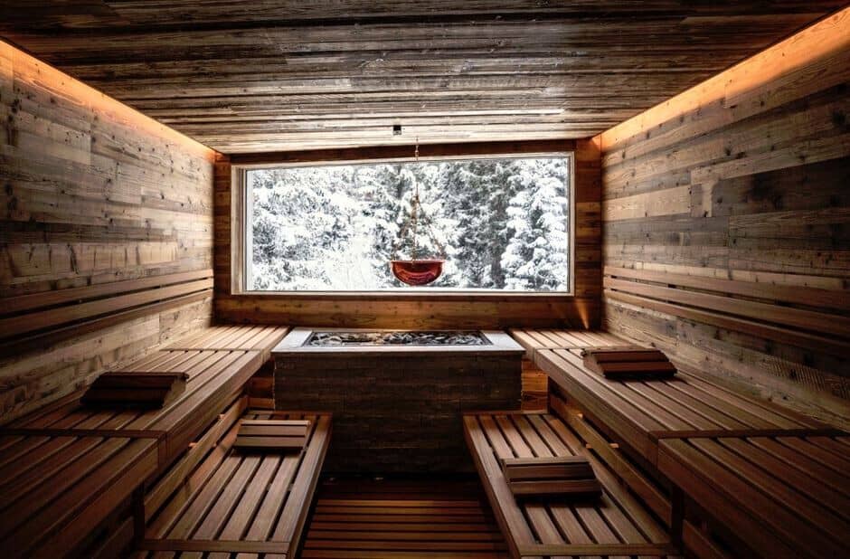 Sauna with tiered seating and large window overlooking snow-covered forest