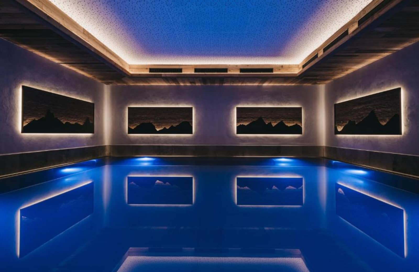 Indoor pool with backlit mountain art and atmospheric mood lighting