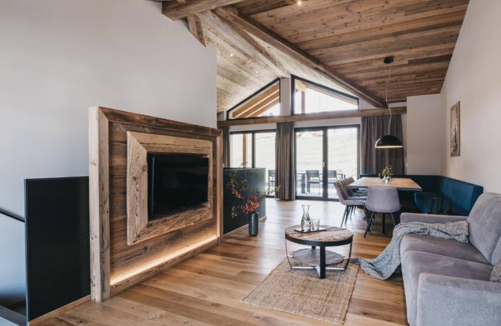 Open-plan living area with vaulted wood ceiling and dining seating for 8