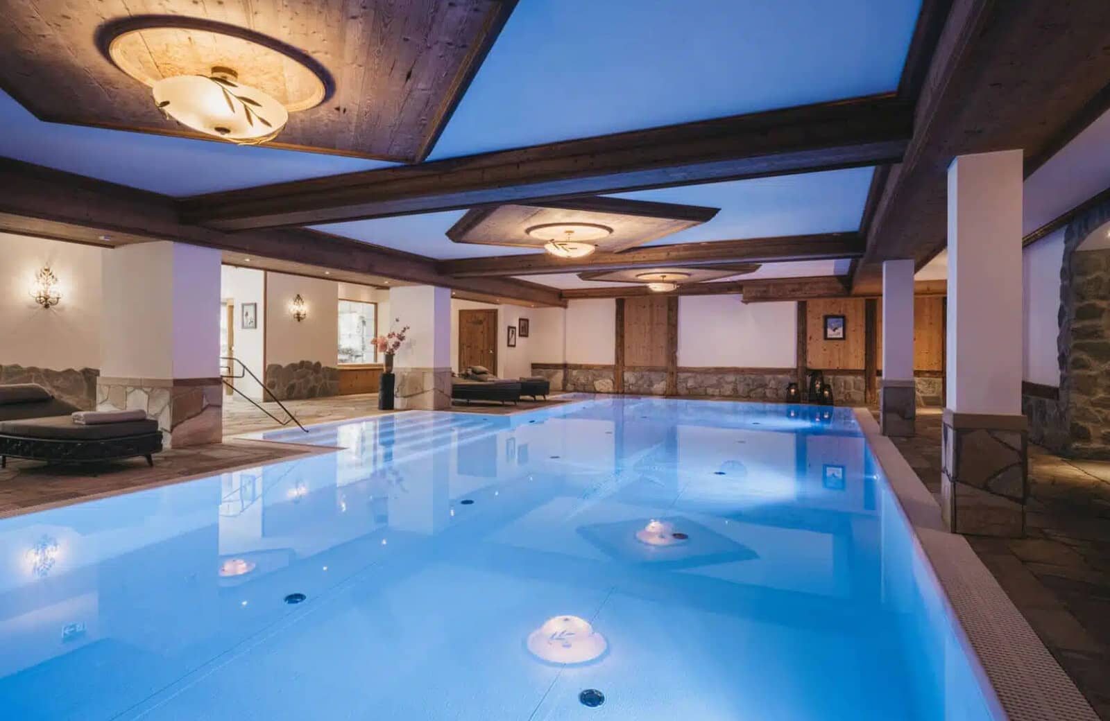 Indoor heated pool with integrated stairs and poolside lounge seating