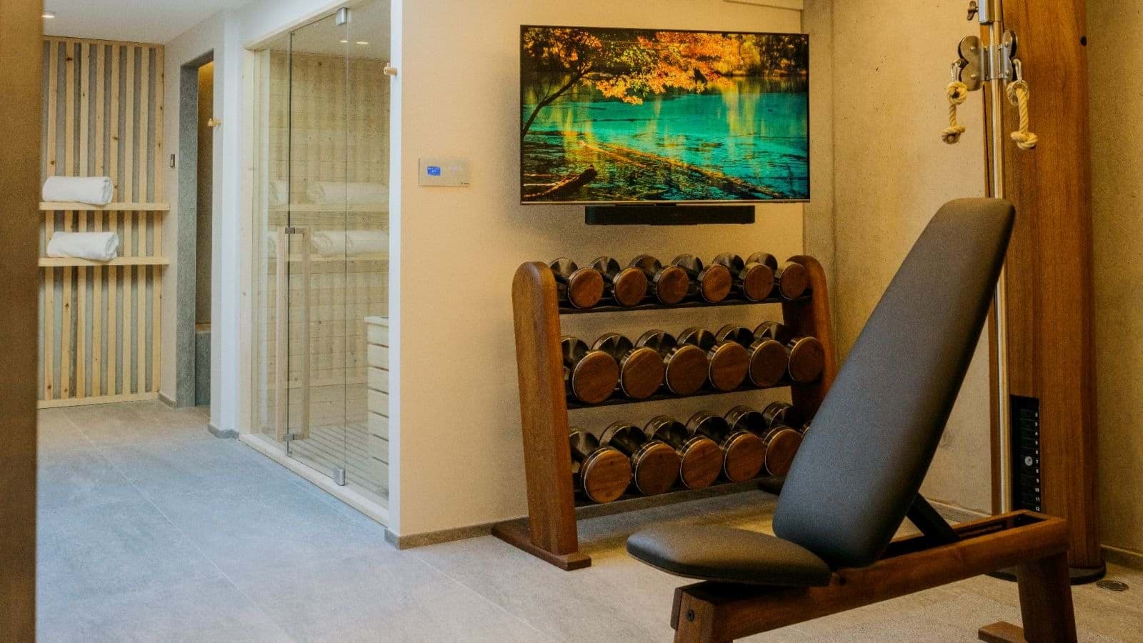 Fitness room with free weights, weight bench, and glass-enclosed sauna