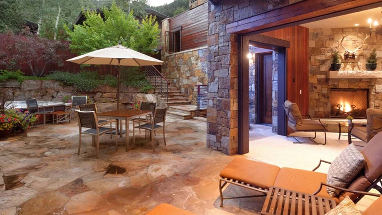 Stone patio with dining for 4, hot tub, and wood-burning outdoor fireplace