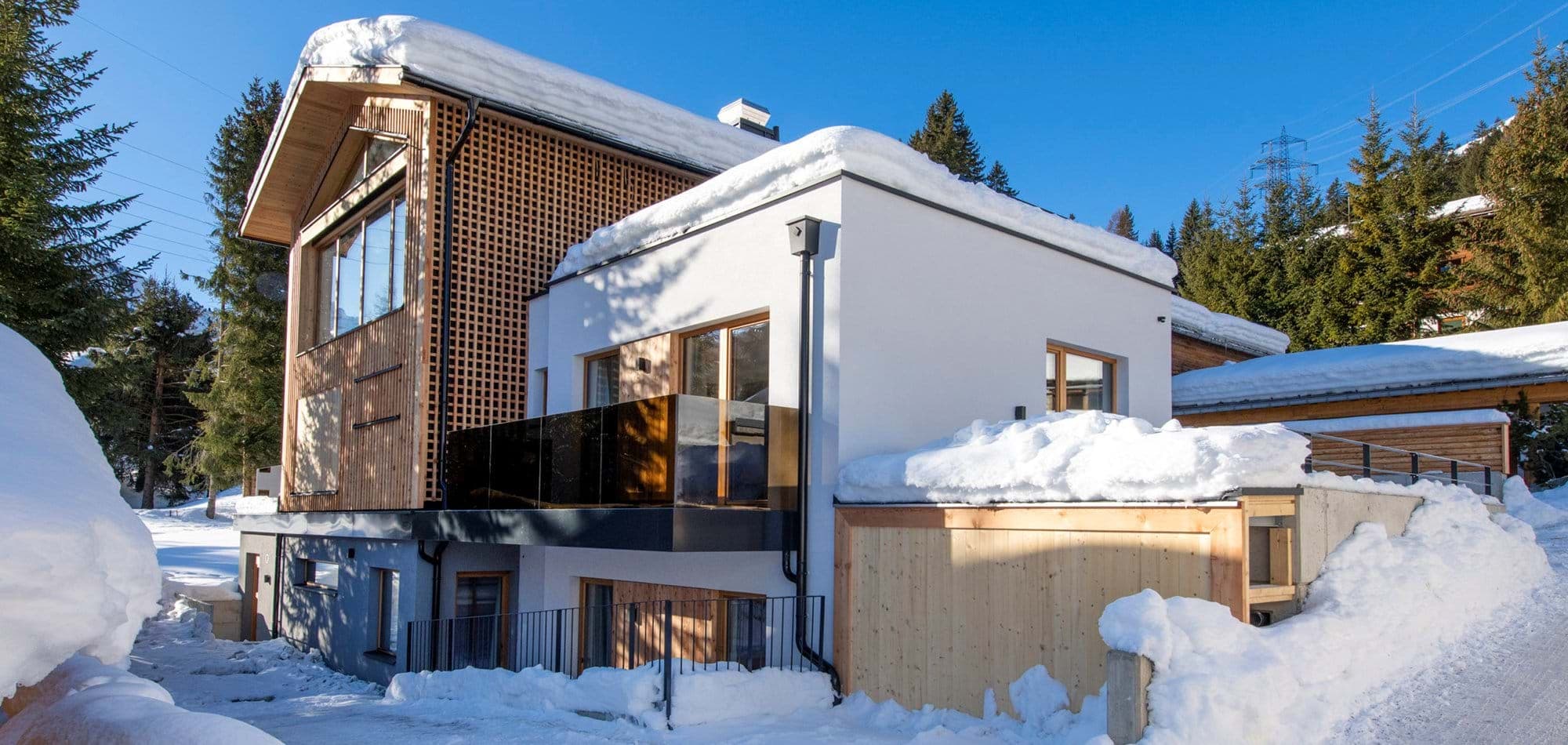 Chalet exterior with private glass balcony and direct snowy trail access