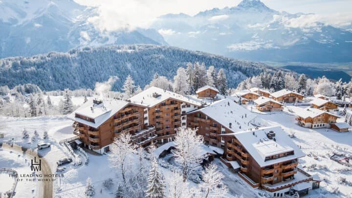 Aerial view of mountain resort featuring multiple chalets and panoramic alpine views