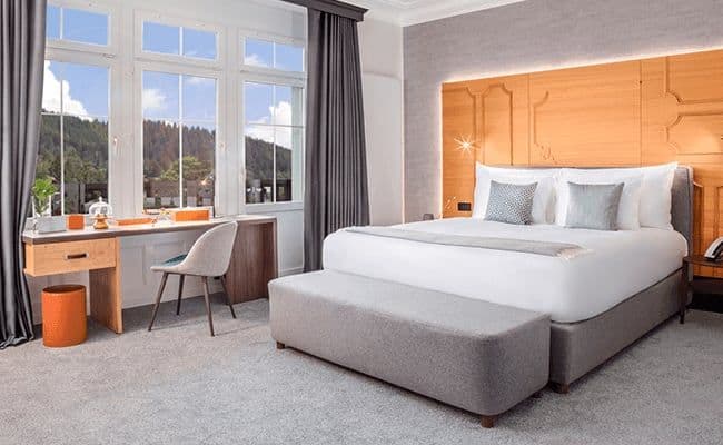 Primary bedroom with king bed and desk overlooking forest