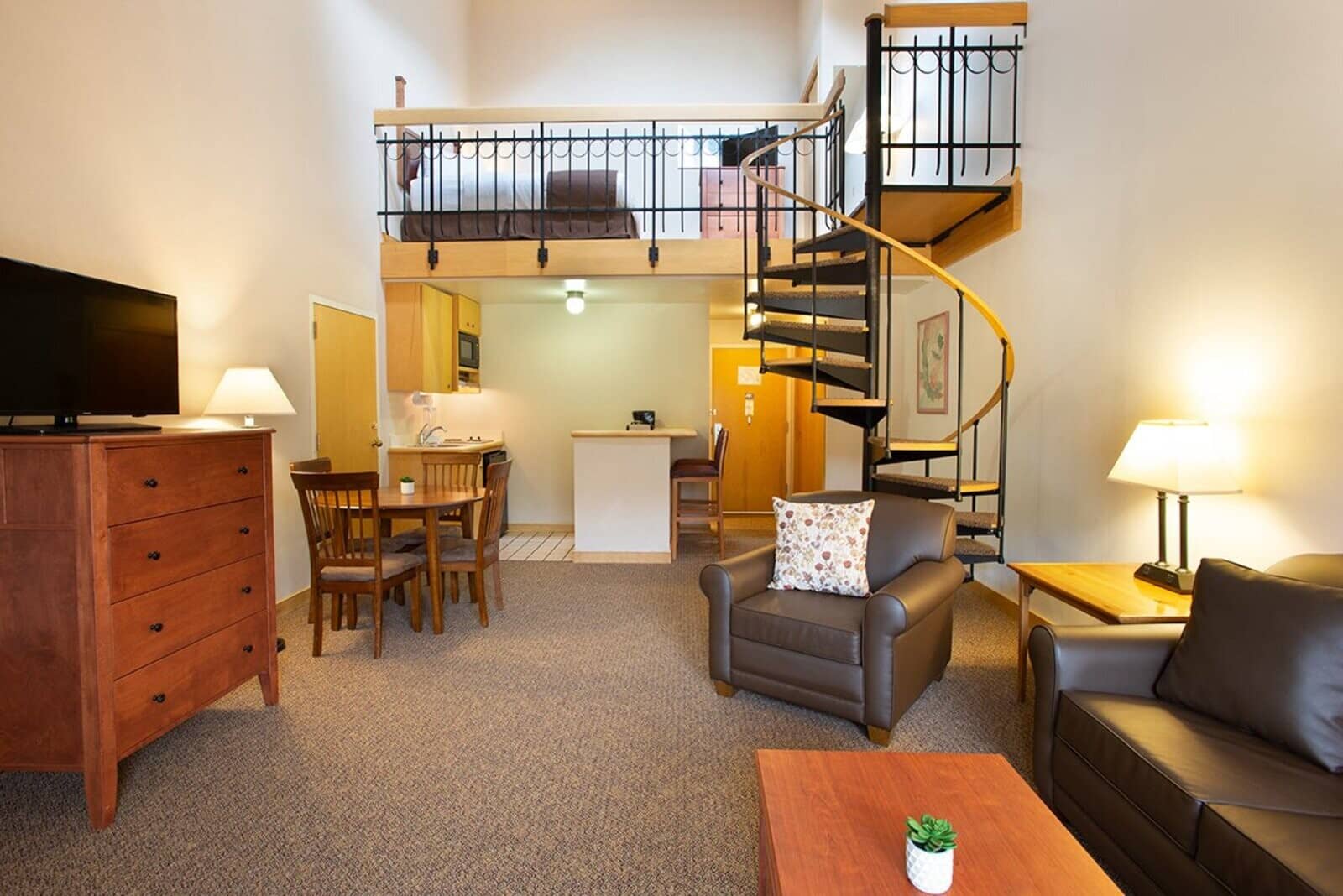 Open-plan living area with spiral staircase leading to lofted bedroom