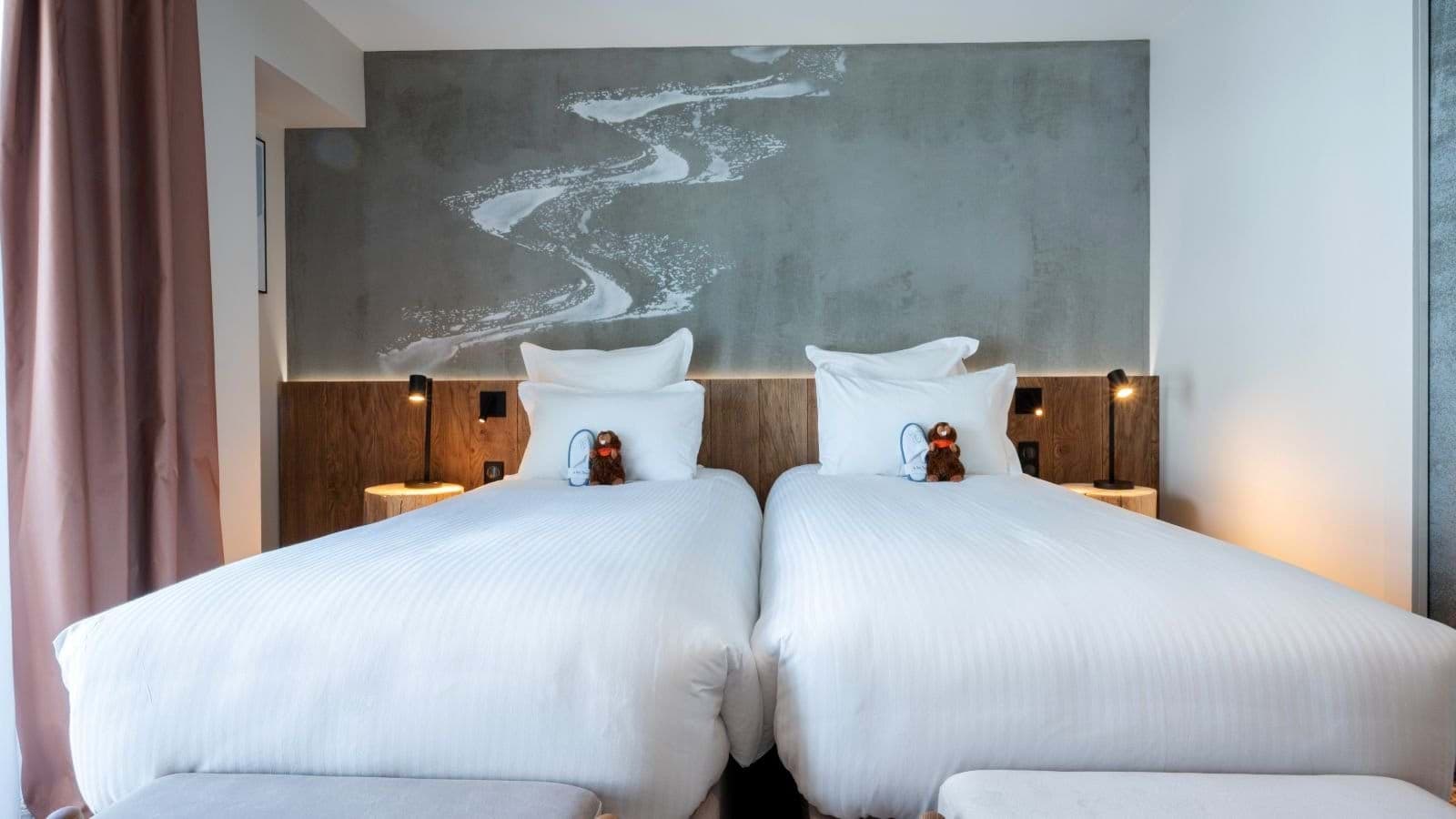Twin beds with individual reading lights and mountain river artwork