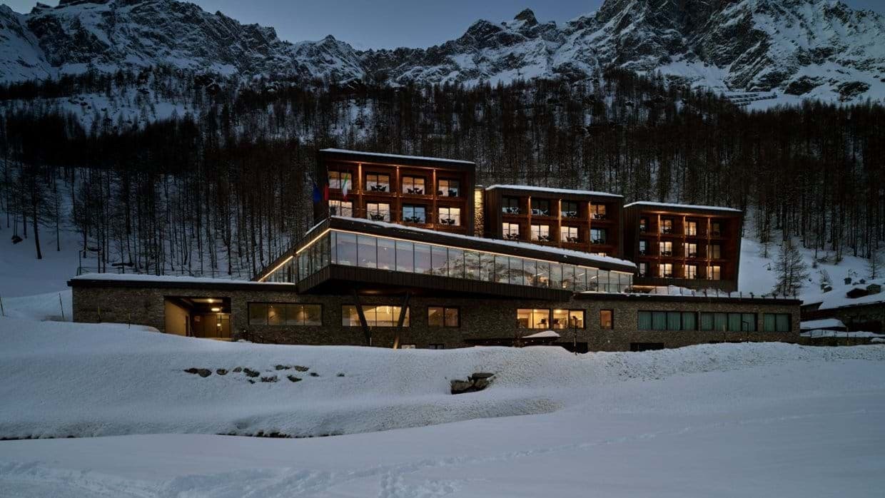 Multi-level resort exterior with floor-to-ceiling windows and mountain backdrop