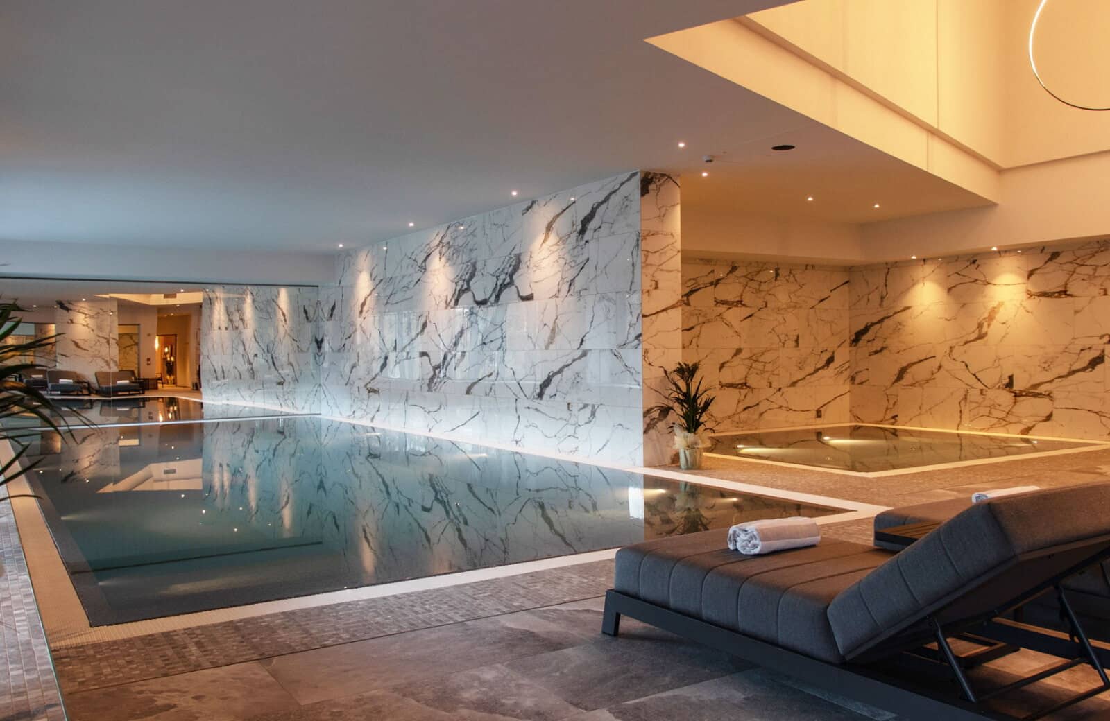 Indoor pool with marble walls and separate hot tub