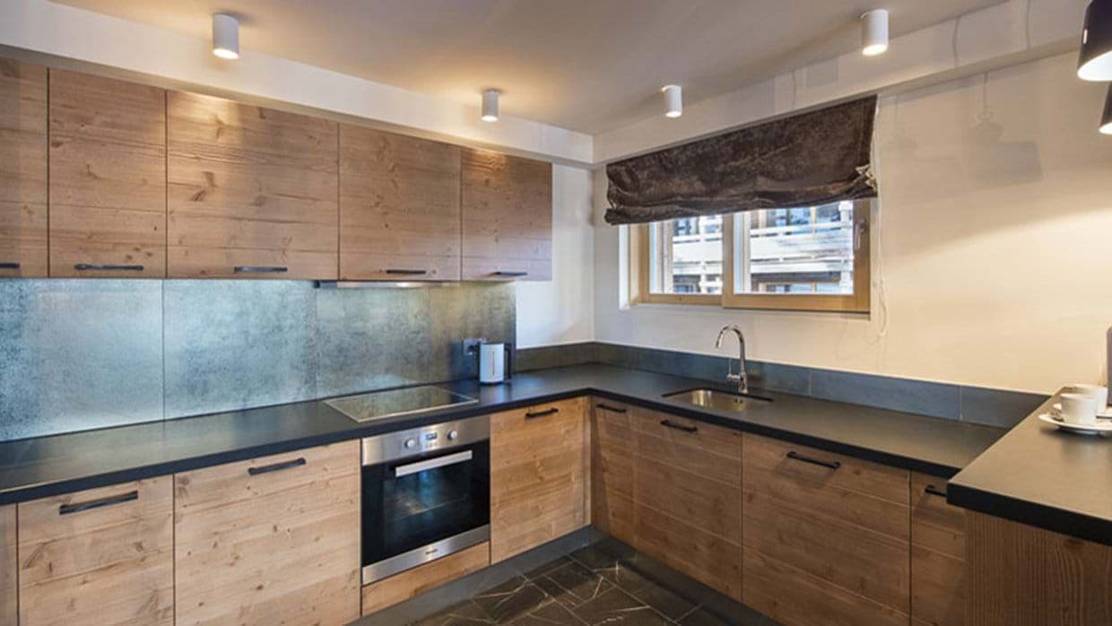 Kitchen with induction cooktop, electric oven, and under-cabinet lighting