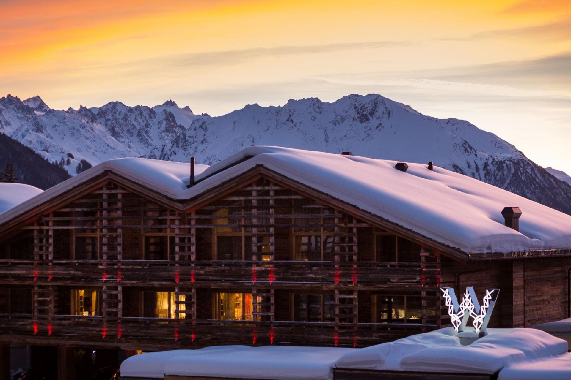 Ski-in, ski-out timber chalet with snow-capped mountain views at sunset