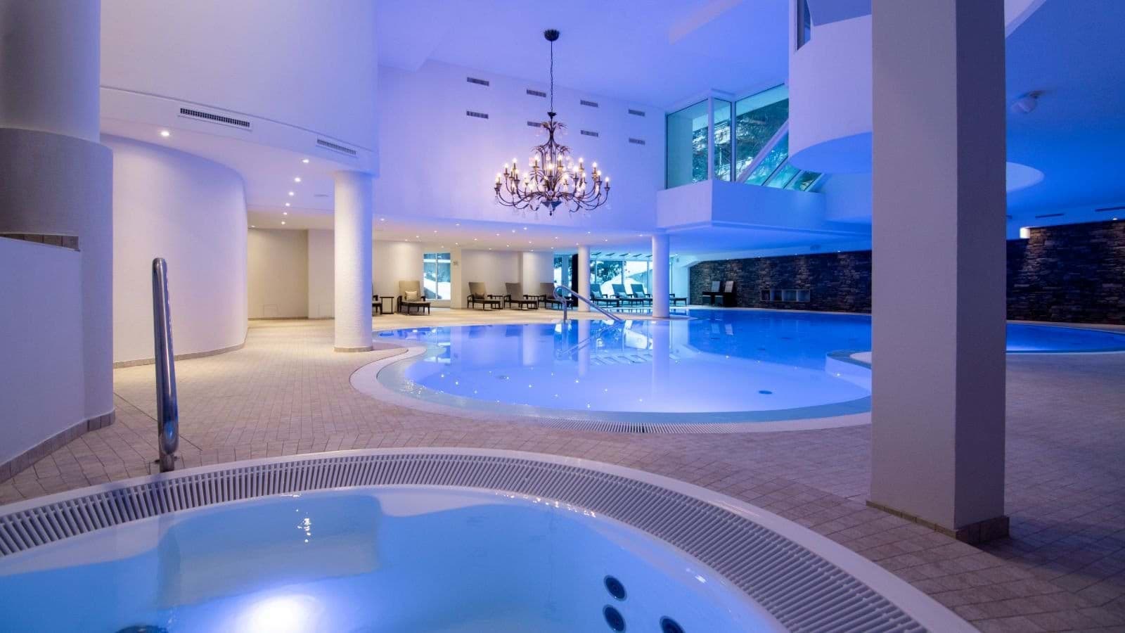 Indoor pool and hot tub with poolside lounge seating
