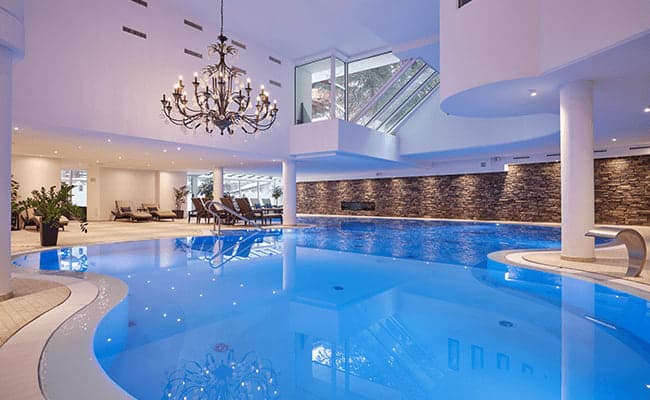 Indoor heated pool with poolside loungers and integrated stone fireplace