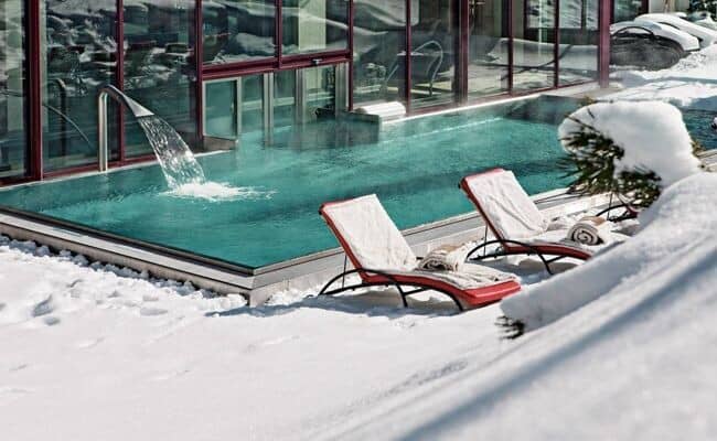 Heated outdoor pool with waterfall feature and poolside loungers
