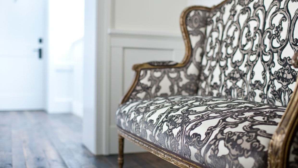 Hallway seating area with vintage damask settee and dark wood flooring