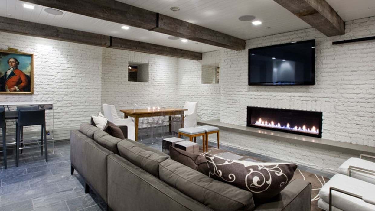 Lower level media room with gas fireplace and exposed brick walls