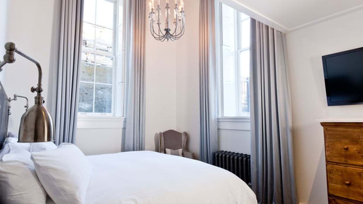 Bedroom with wall-mounted TV, reading lamp, and period radiator