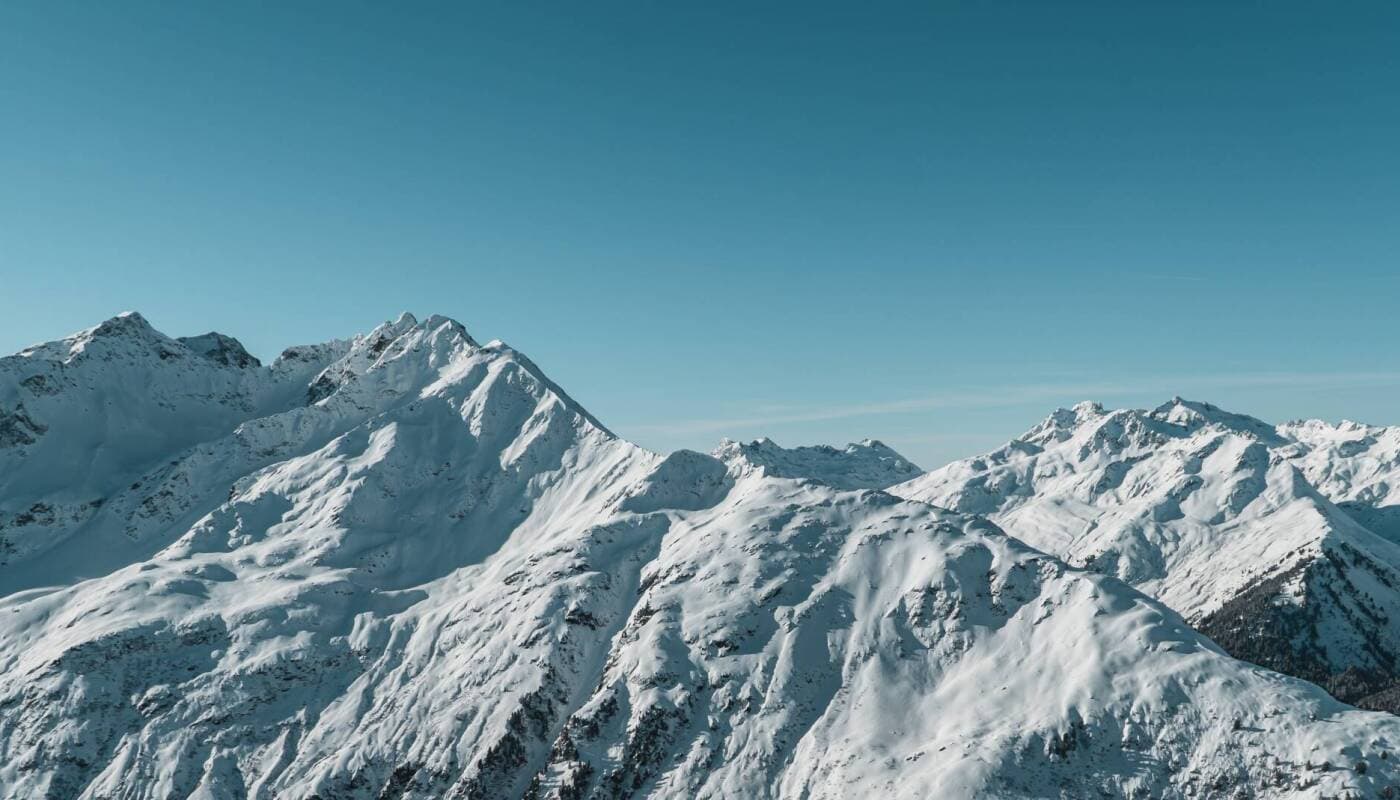 Snow-covered alpine peaks with multiple summits and ski-able terrain visible