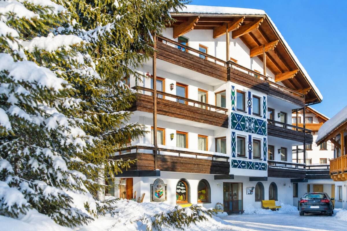 Alpine chalet exterior with blue-and-white balconies; heated ground-level parking