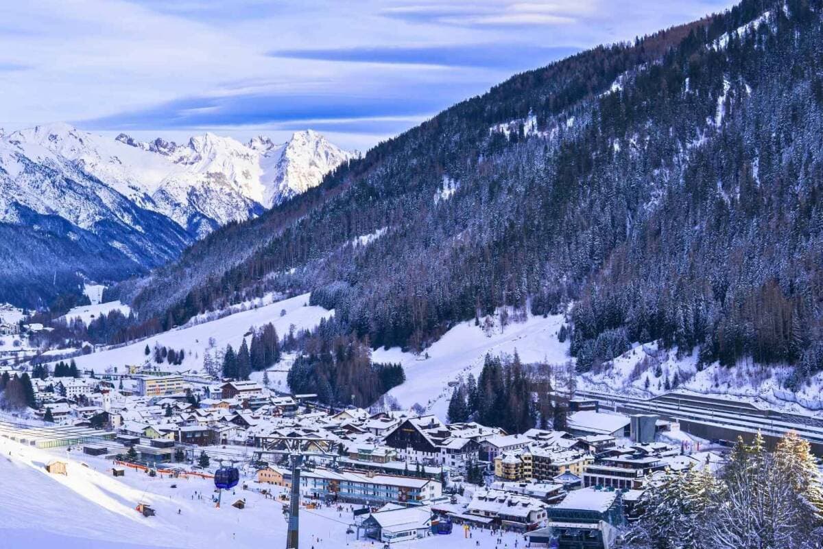 Alpine resort village nestled in snow-covered valley; direct ski lift access visible