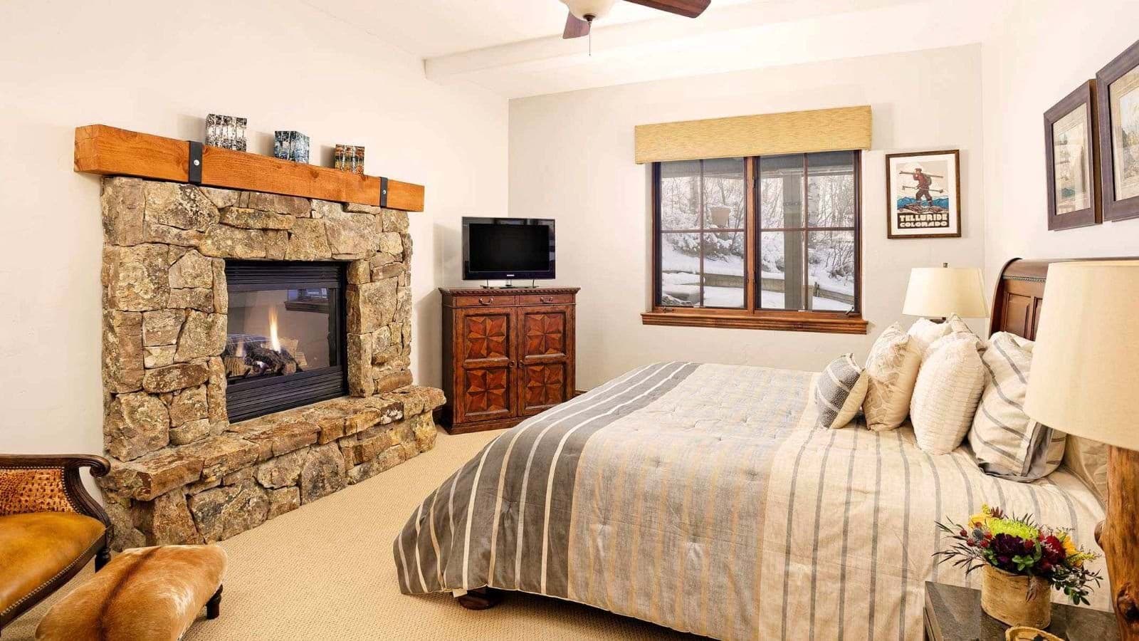 Primary bedroom with gas fireplace and snow-covered patio views