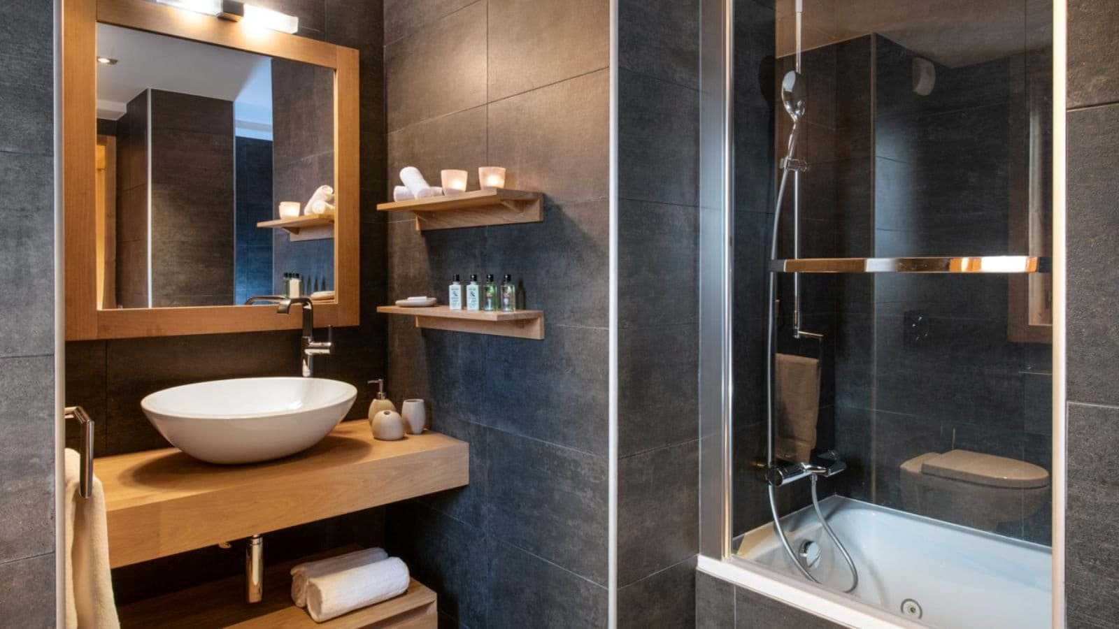 Bathroom with vessel sink and glass-enclosed shower over tub
