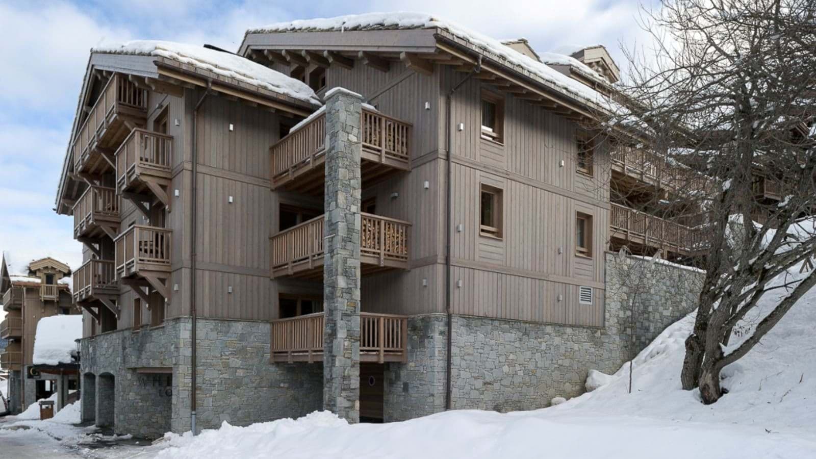 Ski-in ski-out chalet exterior with private balconies and stone masonry