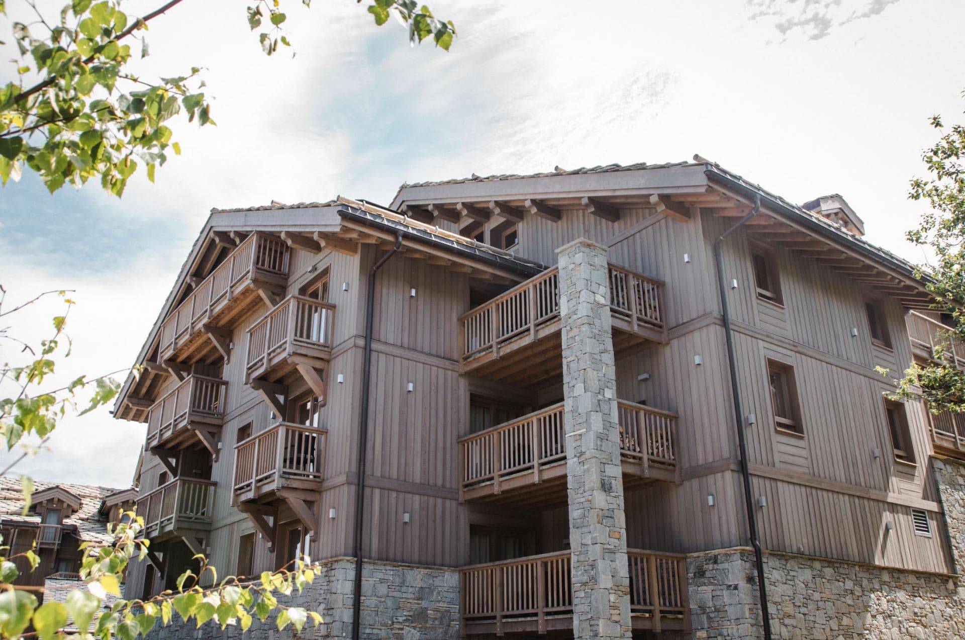 Chalet exterior featuring private timber balconies and stone chimney stack