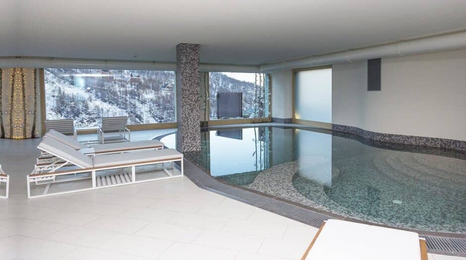 Indoor heated pool with poolside loungers and mountain views