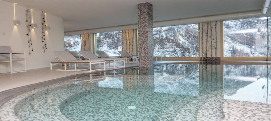 Indoor heated pool with mountain views and poolside lounge seating