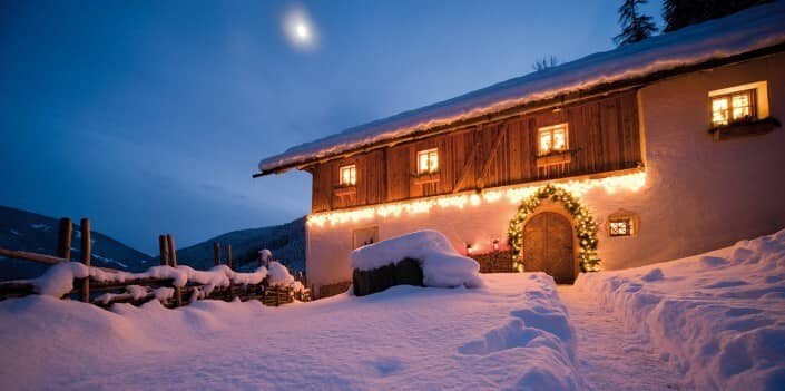 Chalet exterior with arched entrance and snow-covered terrace at twilight