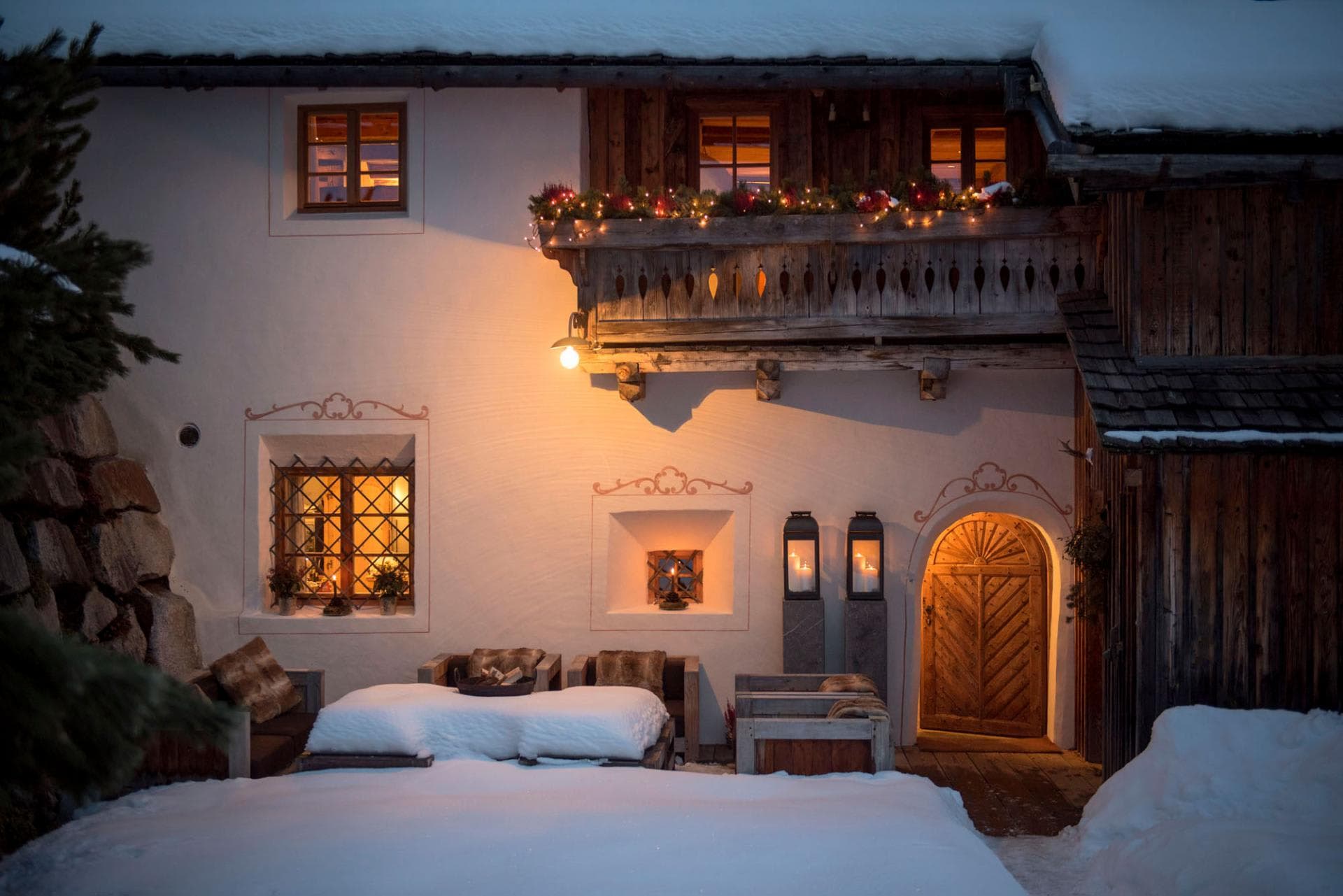 Traditional chalet facade with snow-covered seating and arched wooden entrance