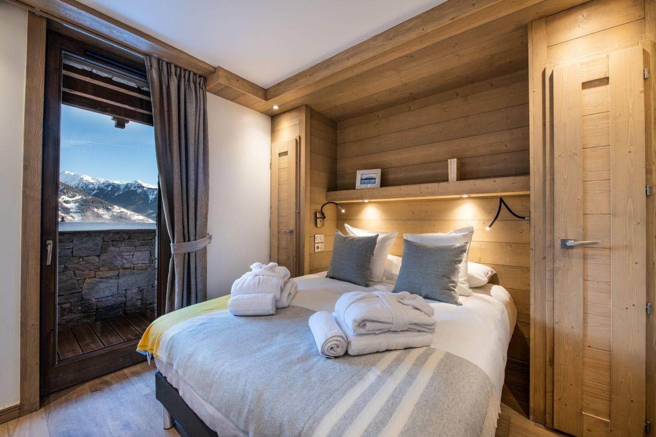 Wood-paneled bedroom with balcony access and mountain views