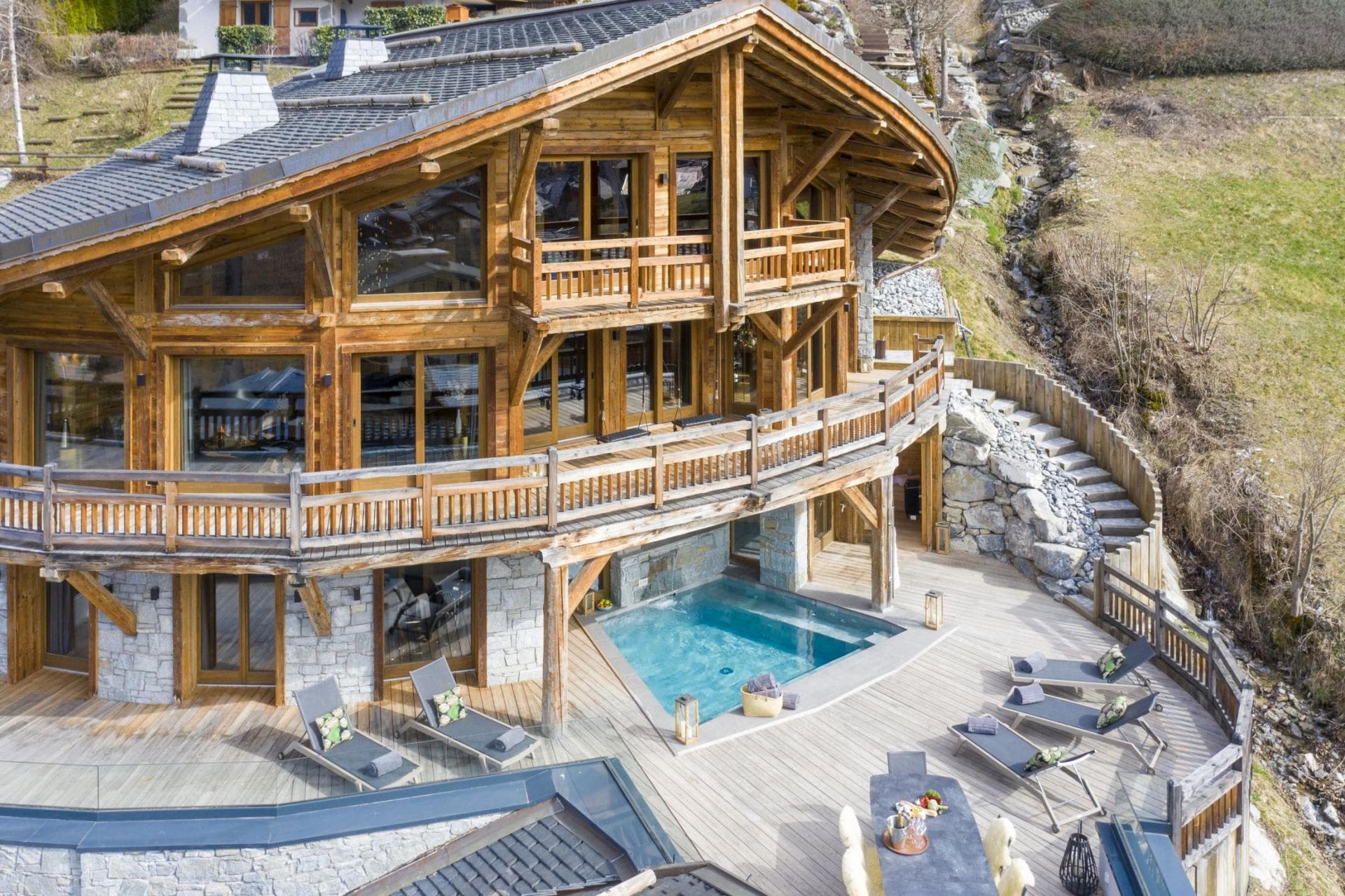 Chalet exterior with heated pool, dining deck, and sun loungers