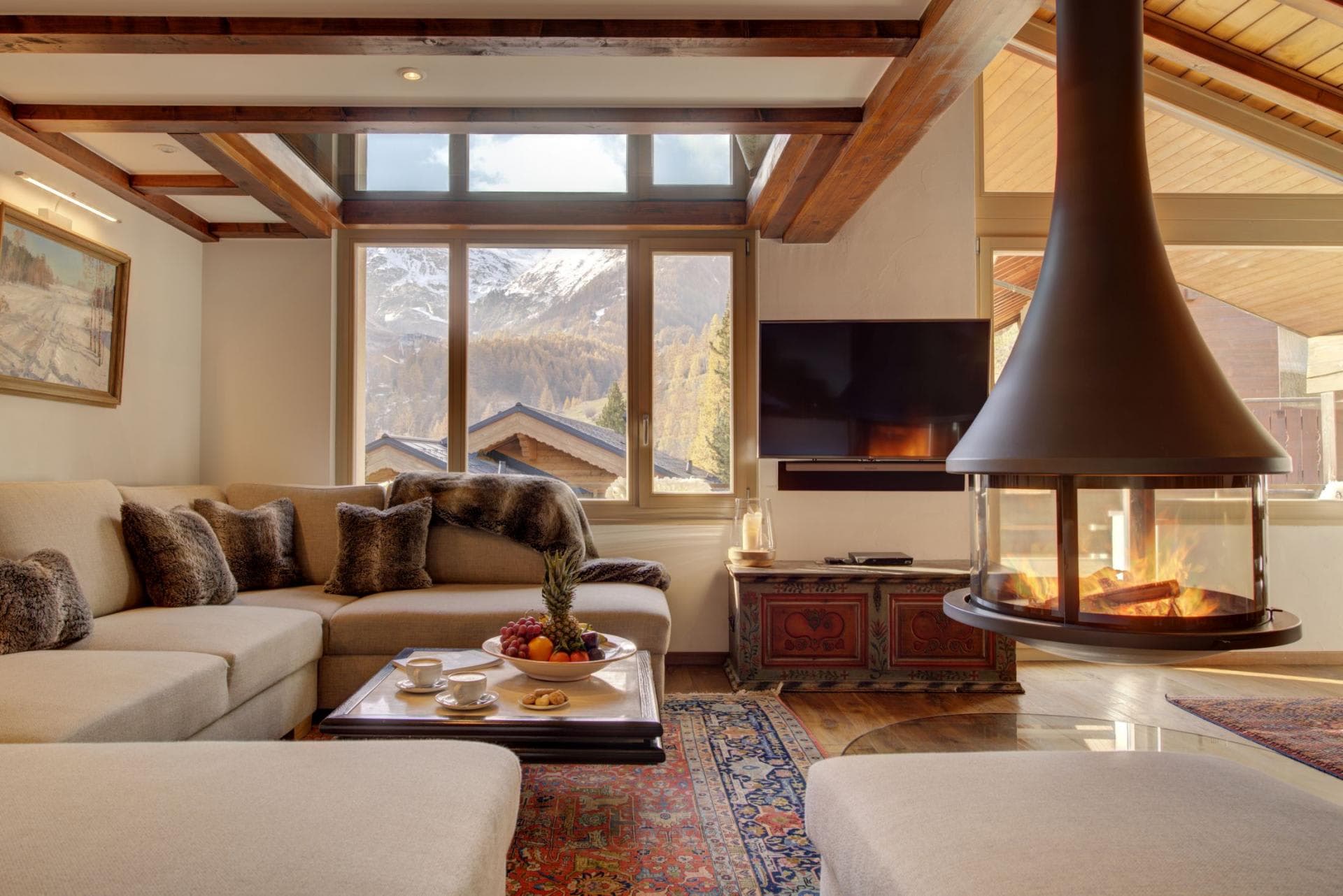 Living room with sectional seating and hanging fireplace; mountain views