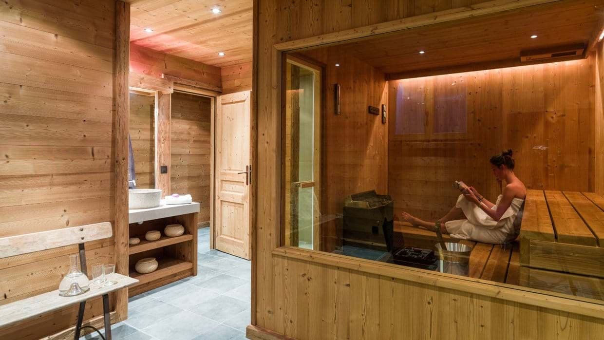 Private sauna with glass wall and adjacent bathroom vanity