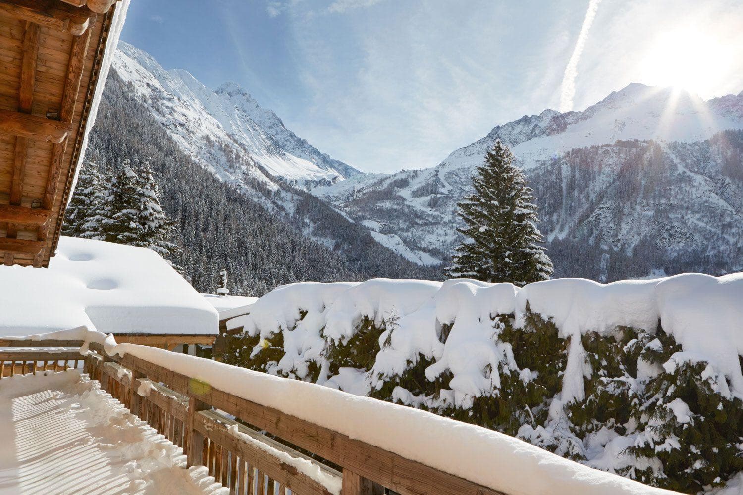 Private balcony with wood railing and views of snow-capped mountains